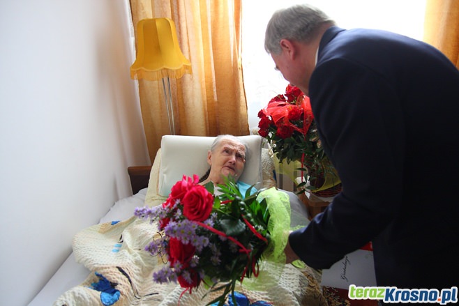 Prezydent Krosna Piotr Przytocki wręcza kwiaty jubilatce